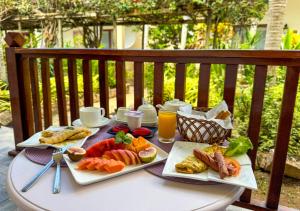 a table with plates of food and drinks on it at Coral Apartments in La Digue