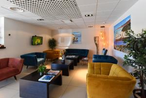 a waiting room with couches and chairs and a tv at Hôtel A Madonetta in Bonifacio