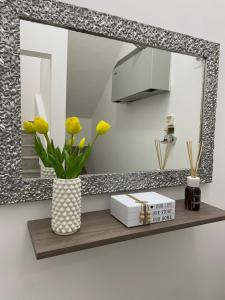a mirror and a vase with yellow flowers on a shelf at Terrasolemonica in Pontecorvo