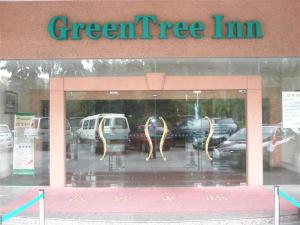 a green tree inn sign in a store window at GreenTree Inn Dongguan Houjie Business Hotel in Dongguan
