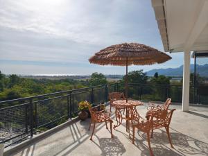 a patio with a table and chairs and an umbrella at Panoramic View & Spacious with Swimming Pool Aza Sunset Villa 1 in Langkawi Intl