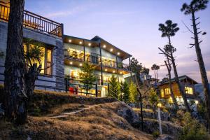 a house on a hill with lights at Pine Country Resort in Mukteshwar