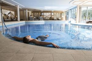 a young man laying in a swimming pool at Meiser SPA Resort in Fichtenau