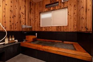a bath tub in a wooden bathroom with a window at Hotaru no Yado Sendou in Yufu +37 photos