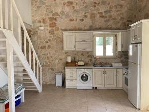 a kitchen with white cabinets and a washer and dryer at Kouvarata Villas Stavros in Vathi