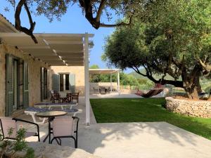 a patio with a table and chairs and a tree at Kouvarata Villas Stavros in Vathi