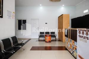 a waiting room with chairs and a flat screen tv at Aster Triplets Guest House JCM Mitra RedDoorz in Yogyakarta