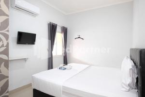 a white bedroom with a bed and a window at Aster Triplets Guest House JCM Mitra RedDoorz in Yogyakarta +32 photos
