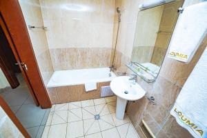 a bathroom with a shower and a sink and a tub at LOUMIA Residency in Douala