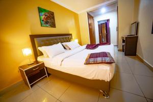 a bedroom with a large bed with a night stand and a lamp at LOUMIA Residency in Douala