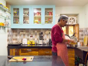 a man standing in a kitchen preparing food at Jaipur Jantar Hostel in Jaipur