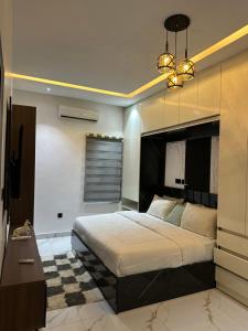 a bedroom with a large bed and a chandelier at Emerald Enclave Residence in Gwarinpa +4 photos