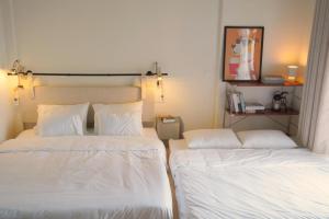 two beds in a room with white sheets and pillows at Lemi - Homestay in Hue in Hue