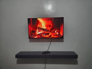 a tv on a wall with a fire in it at Happy Dany Stays in Kiahuria