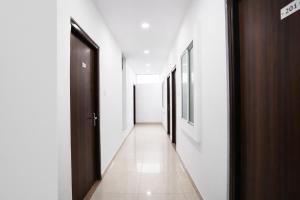 a hallway with white walls and a brown door at FabHotel Shivay in Indore