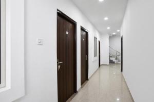 a hallway with wooden doors and white walls at FabHotel Shivay in Indore