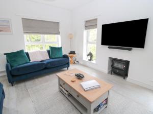 a living room with a couch and a tv on a wall at Summer Rose in Craster