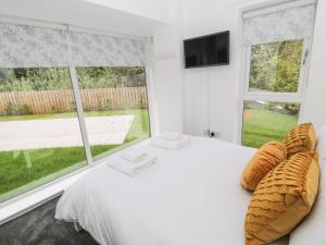 a bedroom with a white bed and a large window at Summer Rose in Craster