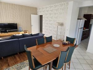 a living room with a table and a blue couch at La Belle des Pins in Mimizan