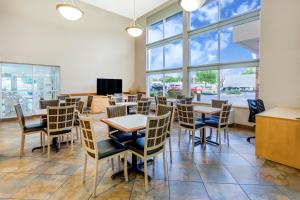 a dining room with tables and chairs and windows at Super 8 by Wyndham Madison South in Madison