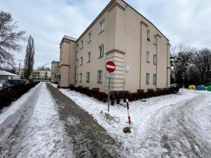 a snow covered road next to a building with a stop sign at Fly Apartment Modlin by JumpInHere in Nowy Dwór Mazowiecki