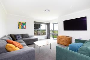 a living room with two couches and a flat screen tv at Mahaki Escape in Pahautea