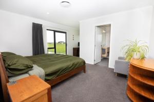 a bedroom with a bed with green sheets and a window at Mahaki Escape in Pahautea