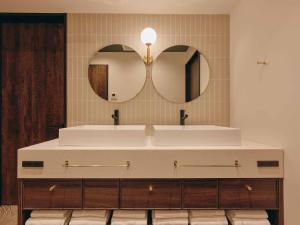 a bathroom with two sinks and two mirrors at illi Eme Tokyo-Toranomon in Tokyo