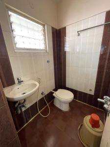 a bathroom with a sink and a toilet and a window at Manjusri Paradise in Bangalore