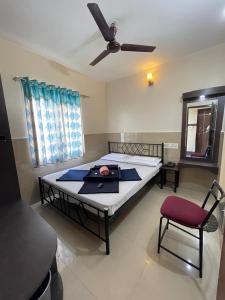 a bedroom with a bed with a ceiling fan and a chair at Manjusri Paradise in Bangalore +4 photos