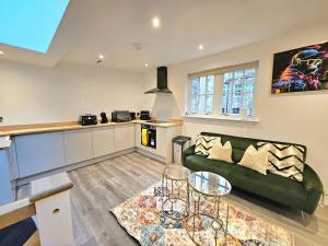 a living room with a green couch and a kitchen at Stylish & Central Design Apartment- 3 Beds in Edinburgh