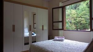 a bedroom with a bed and a large window at Casinha nas montanhas in Gonçalves
