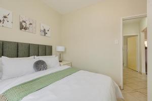 a white bed with a green headboard in a bedroom at Calmwood Stay in Midrand +5 photos