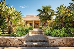 a house with palm trees and a stone walkway at Villa Sirio in Cala de Bou