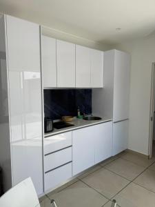 a white kitchen with white cabinets and a sink at Studio on Main in Langebaan +9 photos