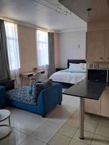 a living room with a bed and a blue couch at Mapungubwe hotel unit 525 in Johannesburg