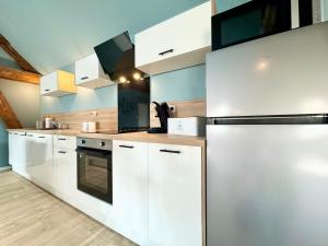 a kitchen with white cabinets and a black refrigerator at Le CoqLoft in Coquelles