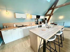 a kitchen with white cabinets and a wooden table at Le CoqLoft in Coquelles