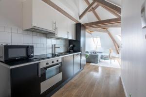 a kitchen with black and white appliances and a living room at Pierres, cloches et vignes in Auxerre