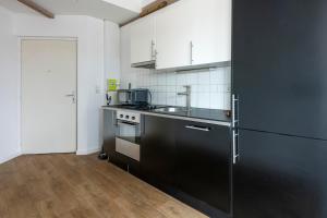 a kitchen with a black refrigerator and a sink at Pierres, cloches et vignes in Auxerre
