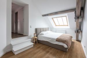 a white bedroom with a bed and a window at Pierres, cloches et vignes in Auxerre