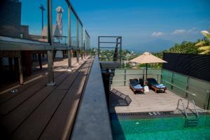 a balcony with two lounge chairs and an umbrella at Lavendish Hills Kandy in Kandy