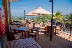 a deck with tables and chairs and an umbrella at Lavendish Hills Kandy in Kandy +22 photos