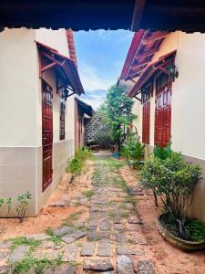 a stone path between two buildings with wooden doors at An's House - Đóng trên booking - LH trực tiếp in Phan Thiet