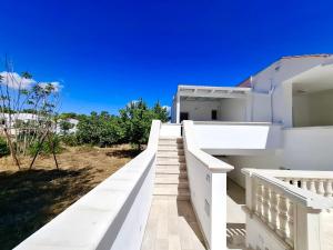 a white house with a white railing and stairs at Serene Sea - Holiday Homes in Marina di Pescoluse