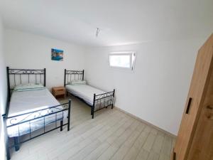 two beds in a room with white walls and wooden floors at Serene Sea - Holiday Homes in Marina di Pescoluse