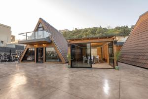 a house with a glass extension with a roof at Wood & Soul - בקתות משולשות מיוחדות עם בריכה פרטית in ‘Isfiyā