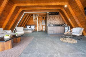 a living room with white furniture and a wooden ceiling at Wood & Soul - בקתות משולשות מיוחדות עם בריכה פרטית in ‘Isfiyā