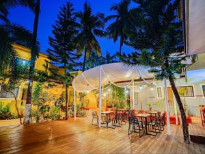 a patio with tables and chairs and palm trees at night at The Hosteller Goa, Anjuna in Arpora