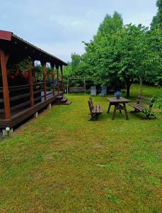 a picnic table and benches in a park at Letniskowy Domek Paullo in Słajszewo +6 photos